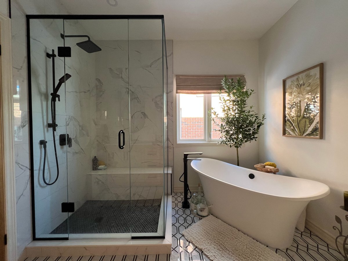 Modern bathroom with a glass-enclosed walk-in shower, white freestanding tub, and geometric patterned tile flooring