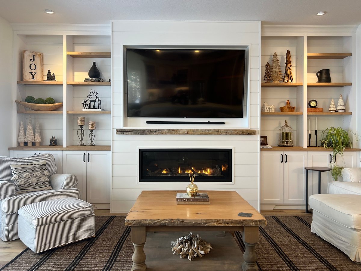 Modern living room with wall-mounted TV, fireplace, built-in shelving, wooden coffee table, and contemporary furnishings