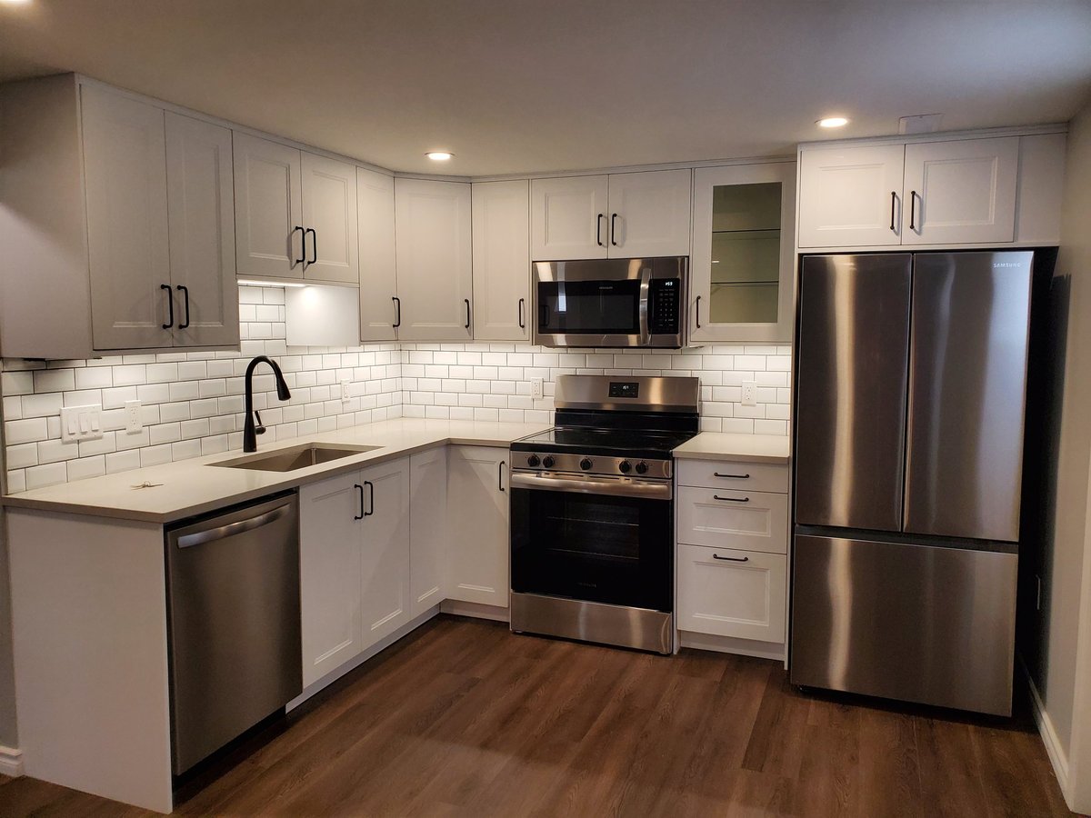 Modern kitchen with white cabinetry, stainless steel appliances, white subway tile backsplash, and hardwood flooring